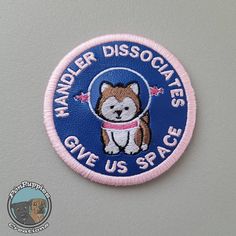 a blue and pink patch with an image of a dog wearing a space suit on it