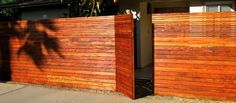 a wooden fence in front of a house with a palm tree on the other side