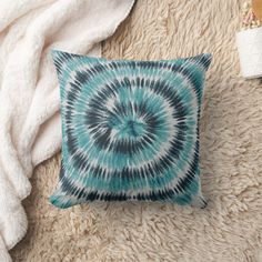 a blue and black tie - dyed pillow sitting on top of a fluffy white blanket