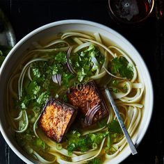 a bowl filled with noodles and tofu on top of a table