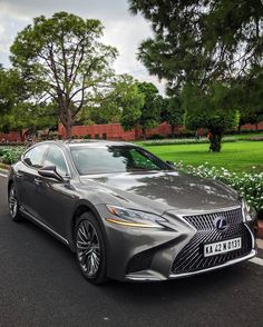 a silver car parked on the side of a road next to trees and bushes in front of a park