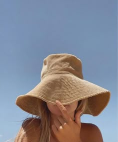 a woman wearing a tan hat on the beach