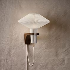 a wall light with a white glass shade on it's head and plugged in