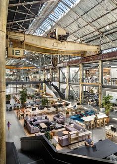 the inside of an industrial building with lots of furniture and plants on it's walls