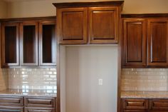 an empty kitchen with wooden cabinets and white tile backsplashes on the walls