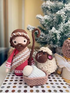 three crocheted nativity figurines sitting next to a christmas tree