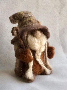 a small stuffed animal wearing a hat and scarf on top of a white sheeted surface