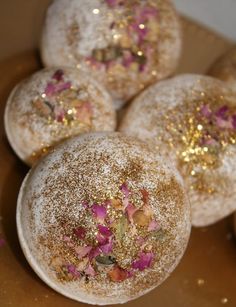 four donuts covered in powdered sugar and sprinkled with gold flakes