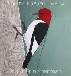 a red and black bird sitting on top of a wooden tree branch next to a green wall