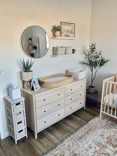 a baby's room with a crib, dresser and mirror on the wall