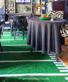 a dining room with green carpeting and zebra print pillows on the wall, black tablecloths and chairs