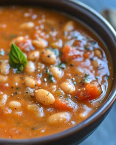 a close up of a bowl of soup with beans and carrots in it on a table