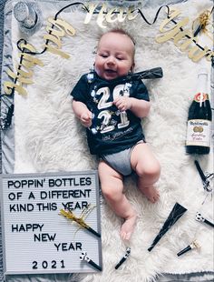 a baby laying on top of a white blanket next to some bottles and confetti