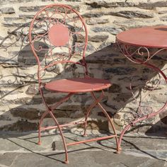 two pink chairs and table against a stone wall