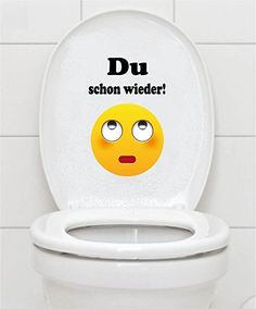 a white toilet with an emoticive sticker on the lid that says, du schon wieder