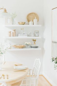 a dining room table with plates and vases on top of the shelves above it