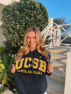 a woman is holding up a sweatshirt that says ucsb santa barbara on the front