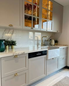 a kitchen with white cabinets and gold trimmings on the glass front cabinet doors