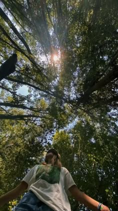 a man standing in the middle of a forest looking up into the sky