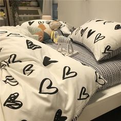 a bed with black and white hearts on the sheets, pillows and pillowcases