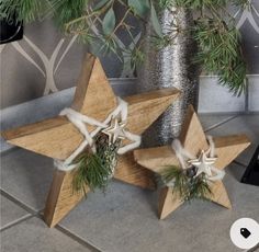 two wooden stars with white bows on them sitting next to a christmas tree in a vase