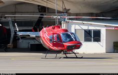 a red helicopter sitting on top of an airport tarmac next to a white building