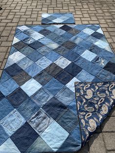 an old patchwork quilt is laying on the ground next to another piece of cloth