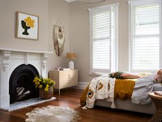 a bedroom with a bed, fireplace and two windows covered in blinds on the side