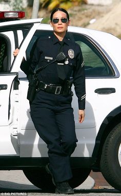 a police officer standing next to a white car with its door open and sunglasses on