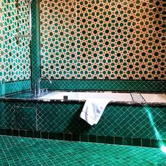 a green tiled bathroom with a bathtub and sink