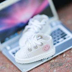 a white shoe sitting on top of a laptop computer