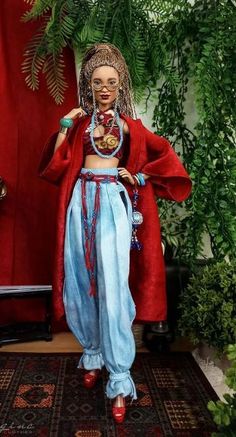 a doll is standing on a rug in front of a red curtain and potted plant