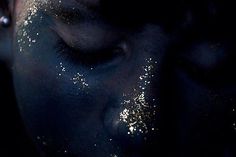 a woman with black and white makeup has glitter on her face as she looks into the camera