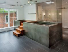 an indoor bathtub in the middle of a room with stairs leading up to it