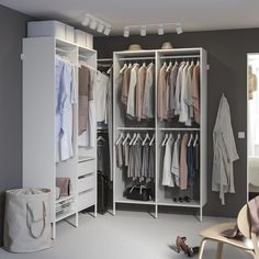 a white closet filled with clothes next to a chair and bag on top of a table