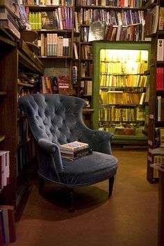 a blue chair sitting in front of a bookshelf filled with lots of books