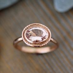 a close up of a ring with a stone in the center on a wooden surface