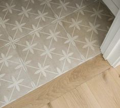 a bathroom floor with white and gray tiles on the bottom, and light wood floors