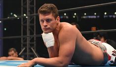 a shirtless man laying on the ground in a wrestling ring