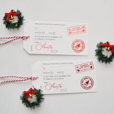 two red and green christmas wreaths are next to some white boarding cards with bows on them