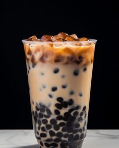 an iced drink with ice and chocolate chips in it on a marble countertop next to a black background