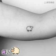 a black and white photo of a small sheep tattoo on the left side of the arm