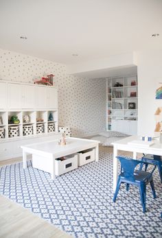 a living room with white furniture and blue rugs on the floor, along with bookshelves