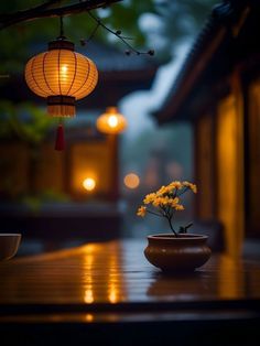 a vase with flowers sitting on top of a wooden table next to a light fixture