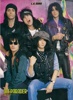 the band kiss posing for a photo in front of a tie dye background with their tongue out