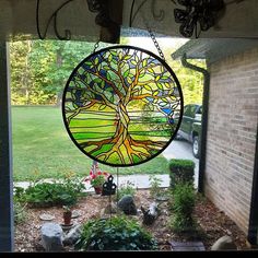 a stained glass tree hanging from the side of a building in front of a car