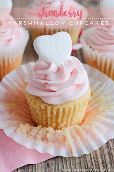 cupcakes with pink frosting and a heart on top are sitting on a paper plate