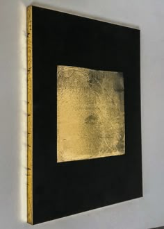 a black and gold painting hanging on the wall next to a white wall with a ruler