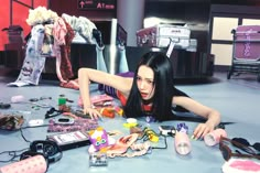 a woman laying on the floor surrounded by assorted toys and other items that are scattered around her