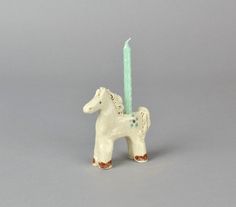 a small white horse figurine with a blue candle